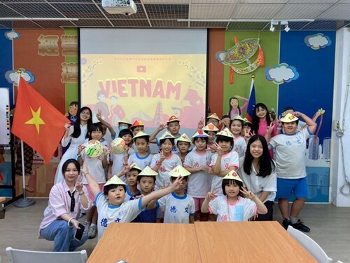 Students from Wende Elementary School pose for a cheerful photo with the Vietnamese presenters while wearing traditional conical hats, a symbol of Vietnamese culture.(Open new window/jpg file)Image
